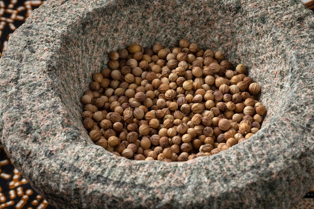 Dried coriander seed in an Asian stone mortar close up