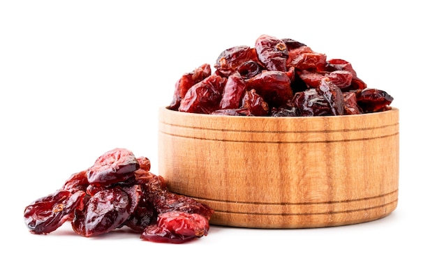 Dried cranberries in a wooden plate and scattered close-up on a white background. Isolated