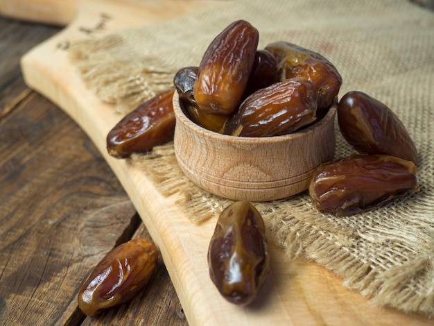 Dried date fruit in bowl on the old wooden table