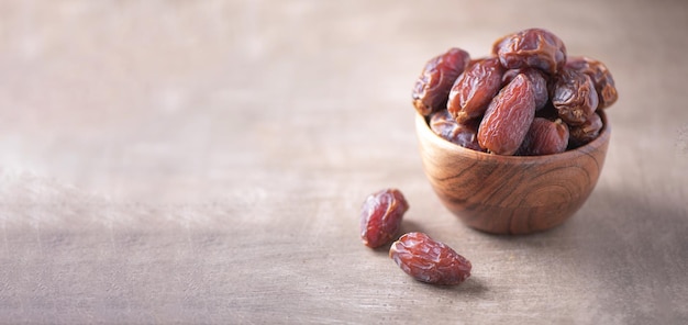 Dried date fruit in wooden bowl on wood textured background Copy space Superfood vegan vegetarian food concept Macro of dates texture selective focus Healthy snack