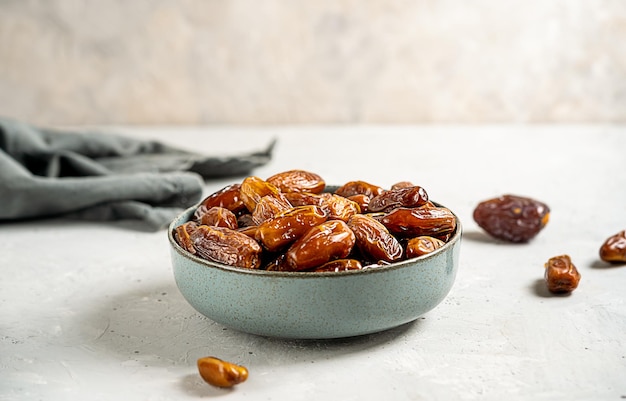 Dried date fruits in a grey bowl with grey napkin on concrete background Close up Copy space