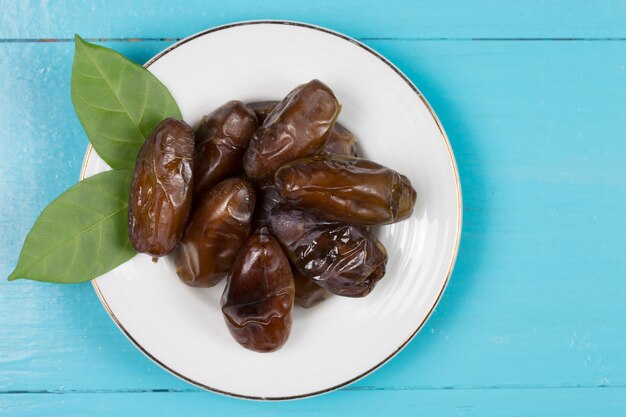 Dried dates in the dish on the wood table.