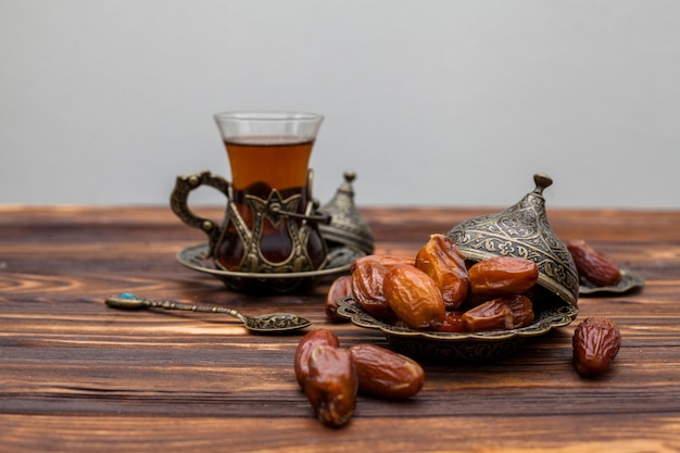 Dried dates fruit on plate with glass of tea 