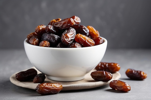 Dried dates in white bowl on grey background