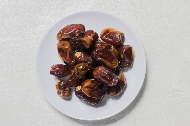 Dried dates on a white plate with isolated background Top angle