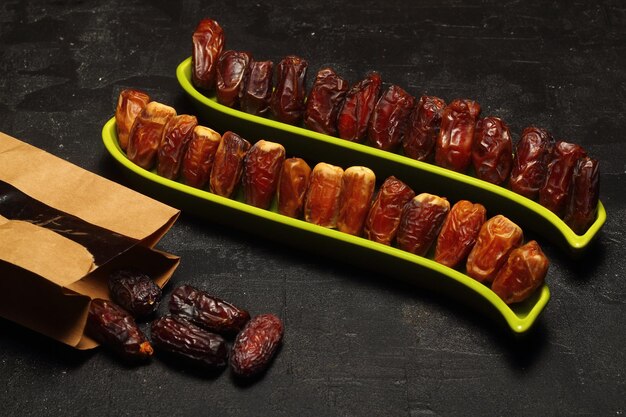 Dried dates on a wooden table in silver dishes closeup Composition of dried dates in ramadan dish