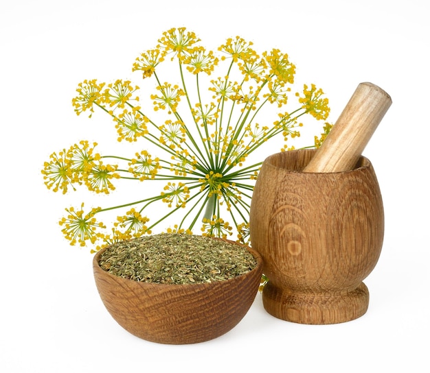 Dried dill crushed in a wooden bowl and a mortar on a white background