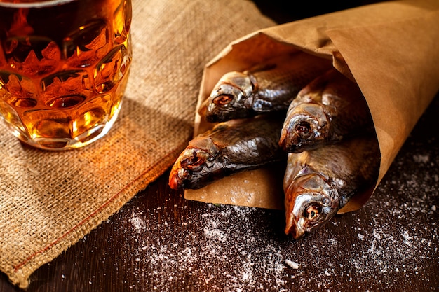 Dried fish and vintage glass of beer on a black surface