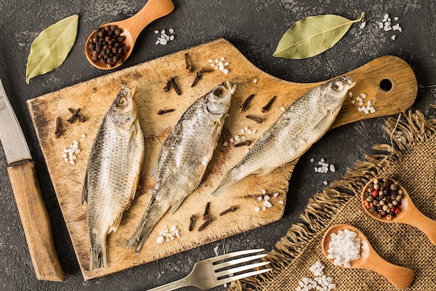 Dried fish with salt and pepper on cutting board