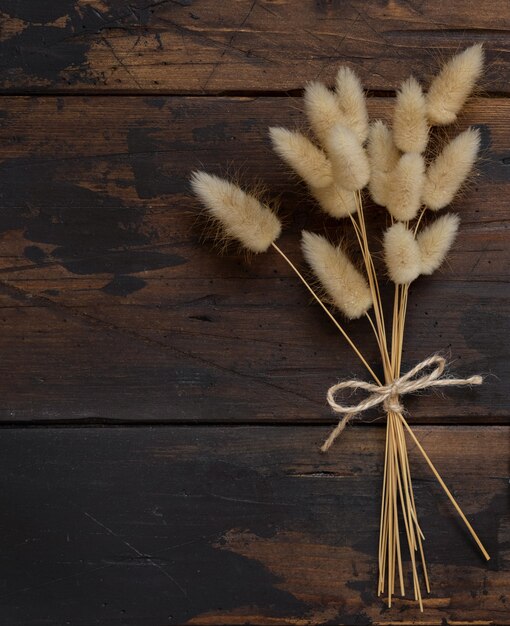 Dried flowers bouquet tied with rope on brown wooden table top view with copy space