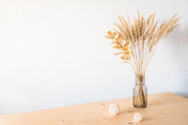 Dried flowers in a glass vase with an empty light wall
