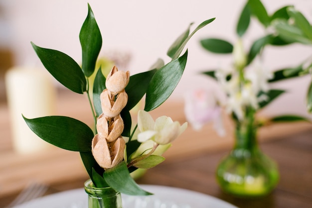 Dried flowers and green leaves in a glass green vase in the interior decor or table