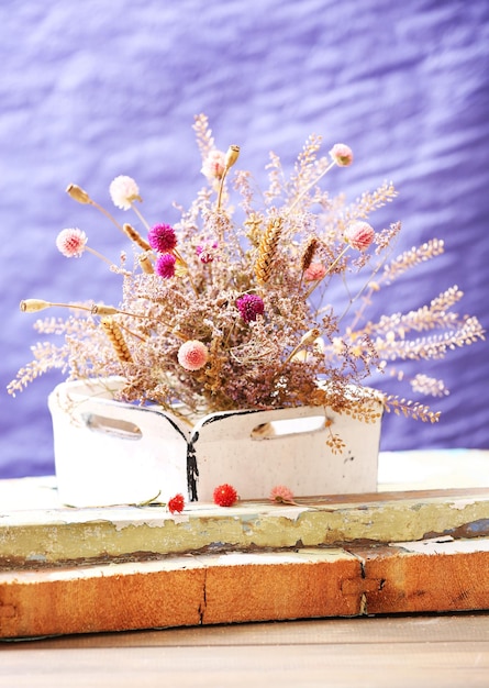 Dried flowers in pot on bright background