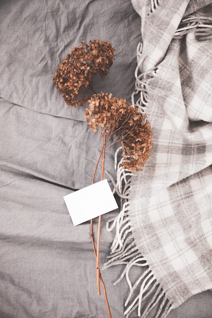 Photo dried flowers romantic bouquet and white empty card stack on bed.