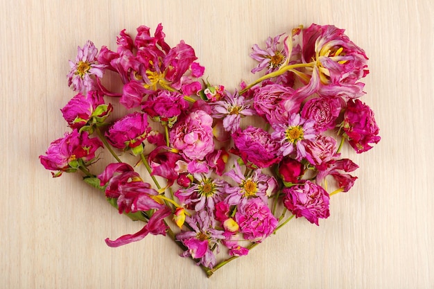 Сухие цветы в форме сердца на деревянном фоне