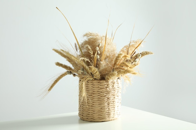 Dried flowers on white table against light background