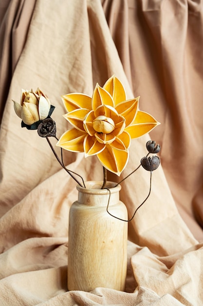 Foto fiori secchi in vaso di legno contro draperia monocromatica natura morta moderna