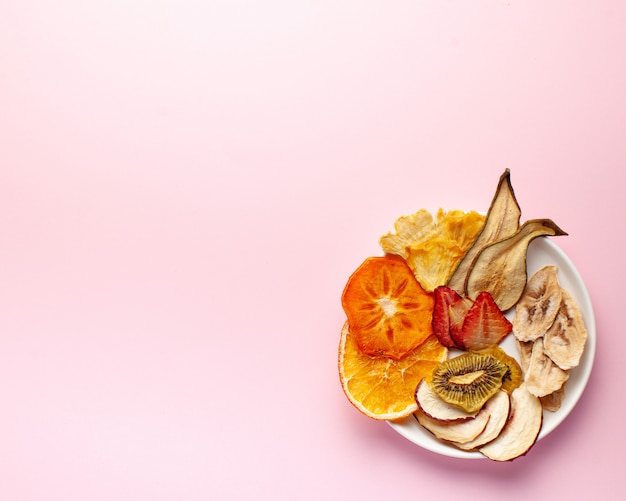 Dried fruit chips on a pink background.