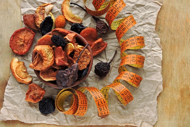 Dried fruits in a bowl and measuring tape. Concept of dried fruits for a slim body.