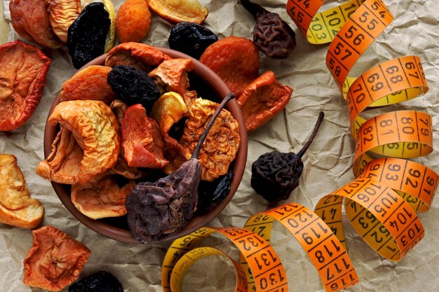 Dried fruits in a bowl and measuring tape. Concept of dried fruits for a slim body.