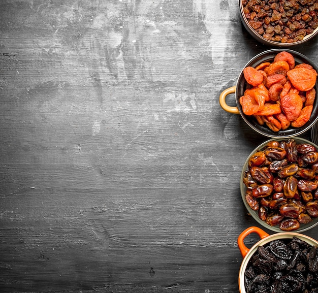 Photo dried fruits in bowls on a black chalkboard