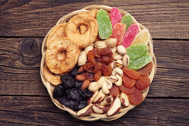 Dried fruits and nuts in a wicker bowl on vintage wooden background