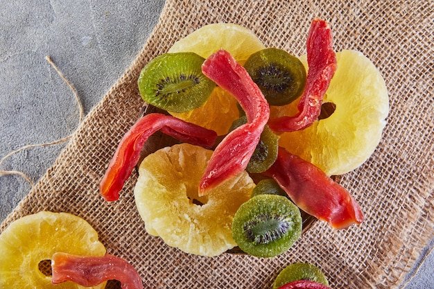 말린 과일 : 삼베에 나무 접시에 노란색 설탕에 절인 파인애플 링, 레드 파파야 및 그린 키위