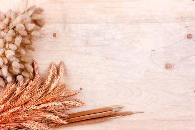 Photo dried grain ears and reeds on a wooden table autumn harvest of bread