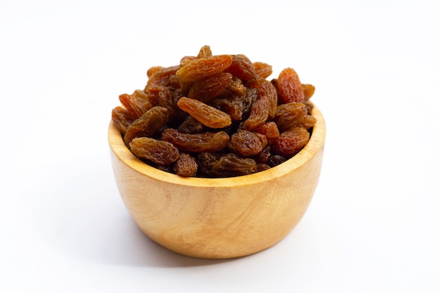 Dried grape raisins in wooden bowl on white background