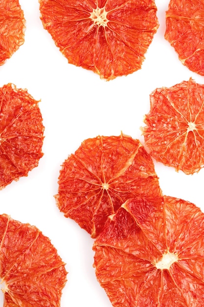Сушеные грейпфруты и апельсины ломтиками на белом фоне Продуктовый фон из сушеных цитрусовых ломтиков