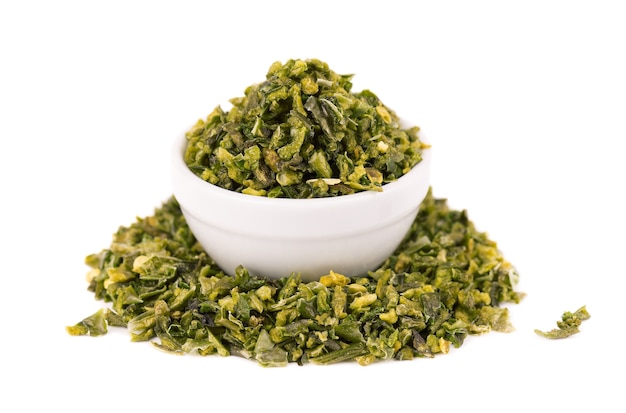 Dried green paprika flakes with seeds in bowl, isolated on white background. Chopped jalapeno, habanero or chilli pepper. Spices and herbs.