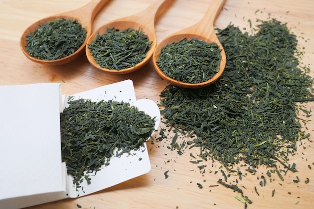 Photo dried green tea in a wooden spoon