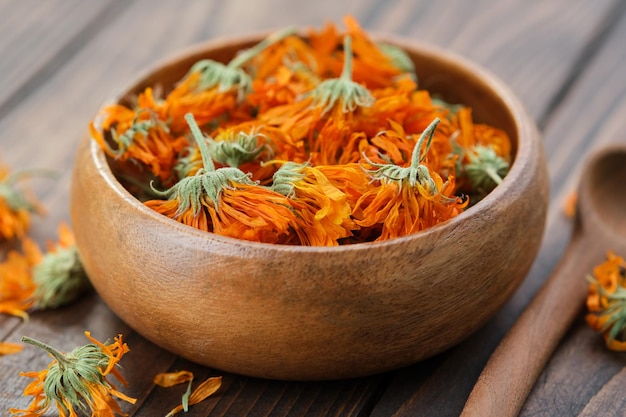 Dried healing calendula flowers in wooden bowl Marigold medicinal herbs Alternative herbal medicine