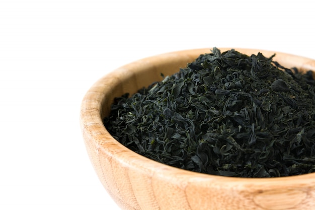 Dried japanese wakame seaweed in a bowl, isolated on white surface