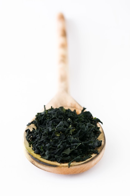 Dried japanese wakame seaweed in wooden spoon isolated on white surface