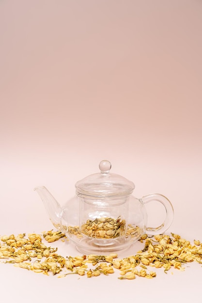Dried jasmine flowers in a teapot on a pink background flower\
tea