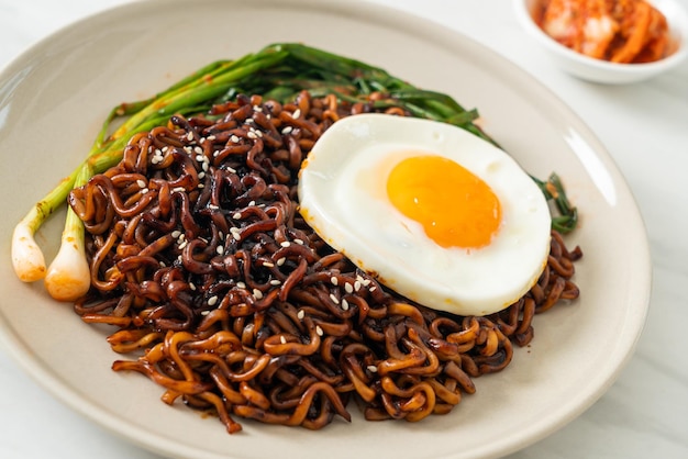 目玉焼きとキムチを添えた韓国の辛い黒醤油インスタントラーメン