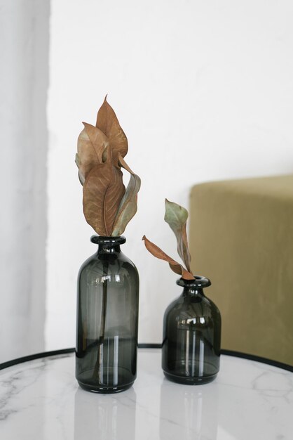 Dried leaves in black glass vases are on the table