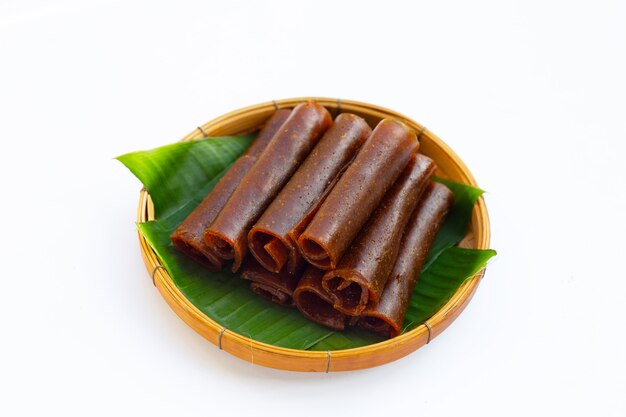 Dried mango paste in bamboo basket on white background.