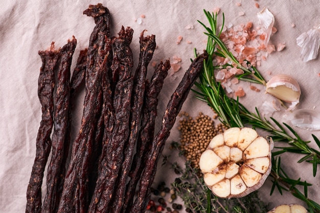 Dried meat beef jerky on tablecloth and wooden surface
