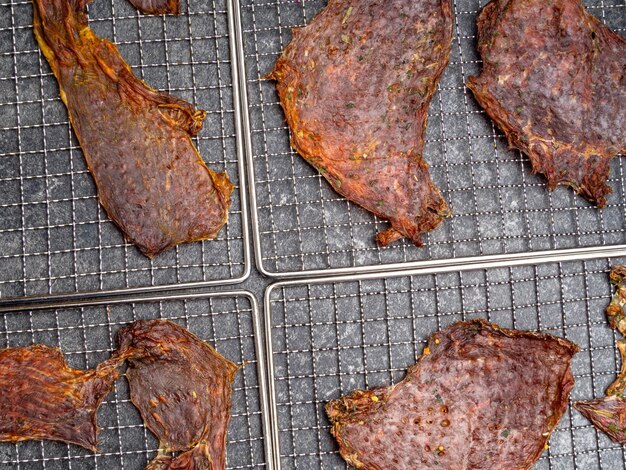 Dried meat slices on metal tray close up