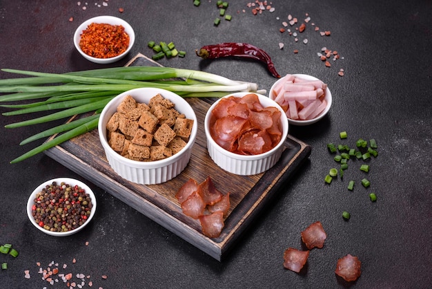 Dried meat slices with spices and herbs Snacks for beer On a black stone background Top view