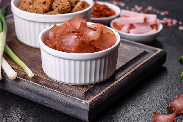 Dried meat slices with spices and herbs Snacks for beer On a black stone background Top view