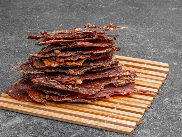 Dried meat slices in wooden board copy space