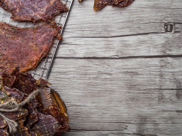 Dried meat slices on wooden surface close up