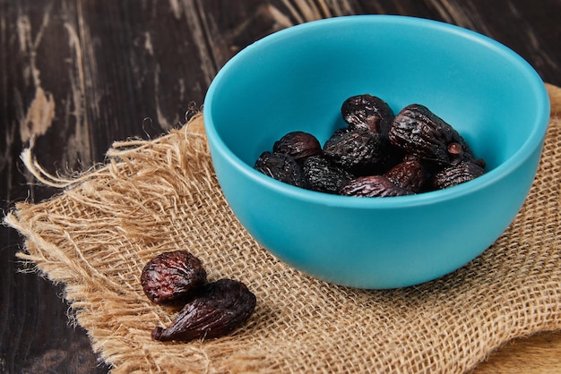 Dried mission figs in glass bowl on burlap and wooden background