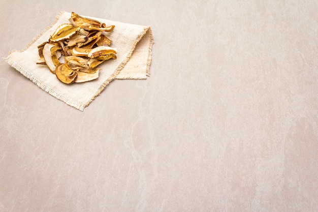 Dried mushrooms boletus edulis (penny bun, cep, porcino). Ingredient for vegetarian (vegan) food. With vintage linen cloth on a stone background, copy space.