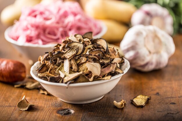 Dried mushrooms sour cabbage garlic and potatoes on wooden table.