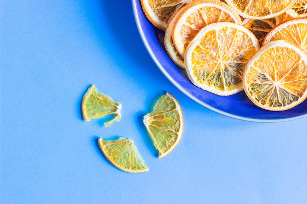 Fette secche della frutta arancio su un piatto ceramico blu, concetto minimo della frutta della carta blu.