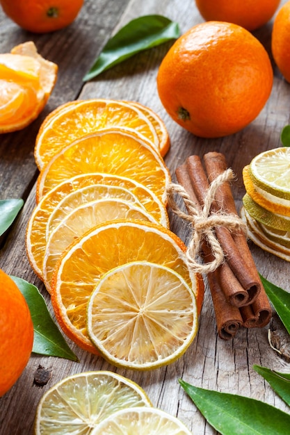 Dried orange and lemon slices cinnamon sticks and ripe tangerines on old table